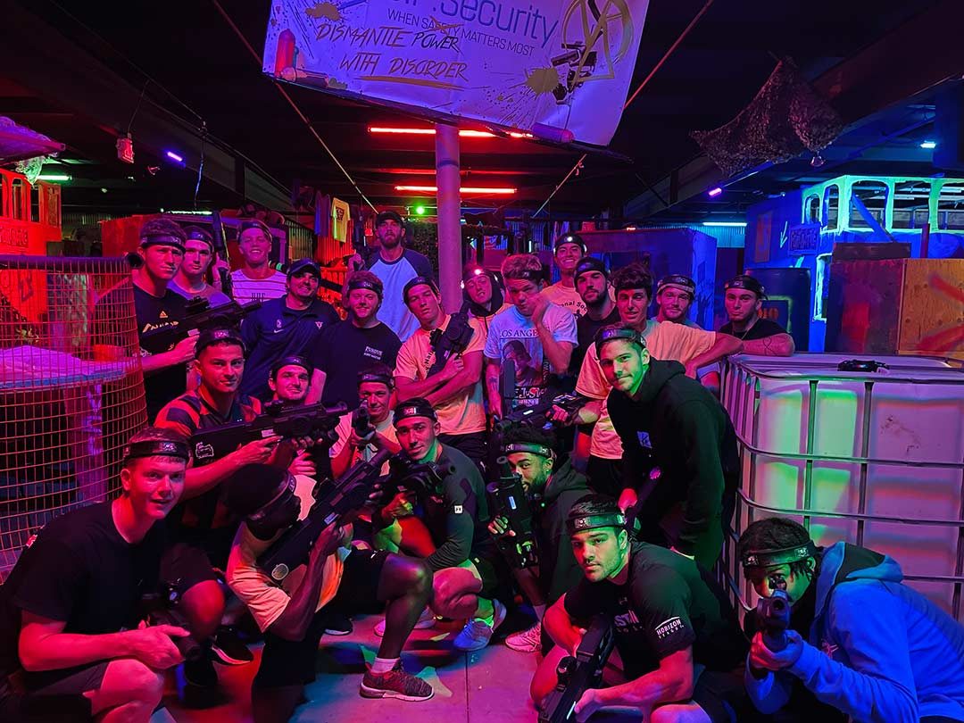 A group in laser tag gear lit by the arena neon at Combat Ops