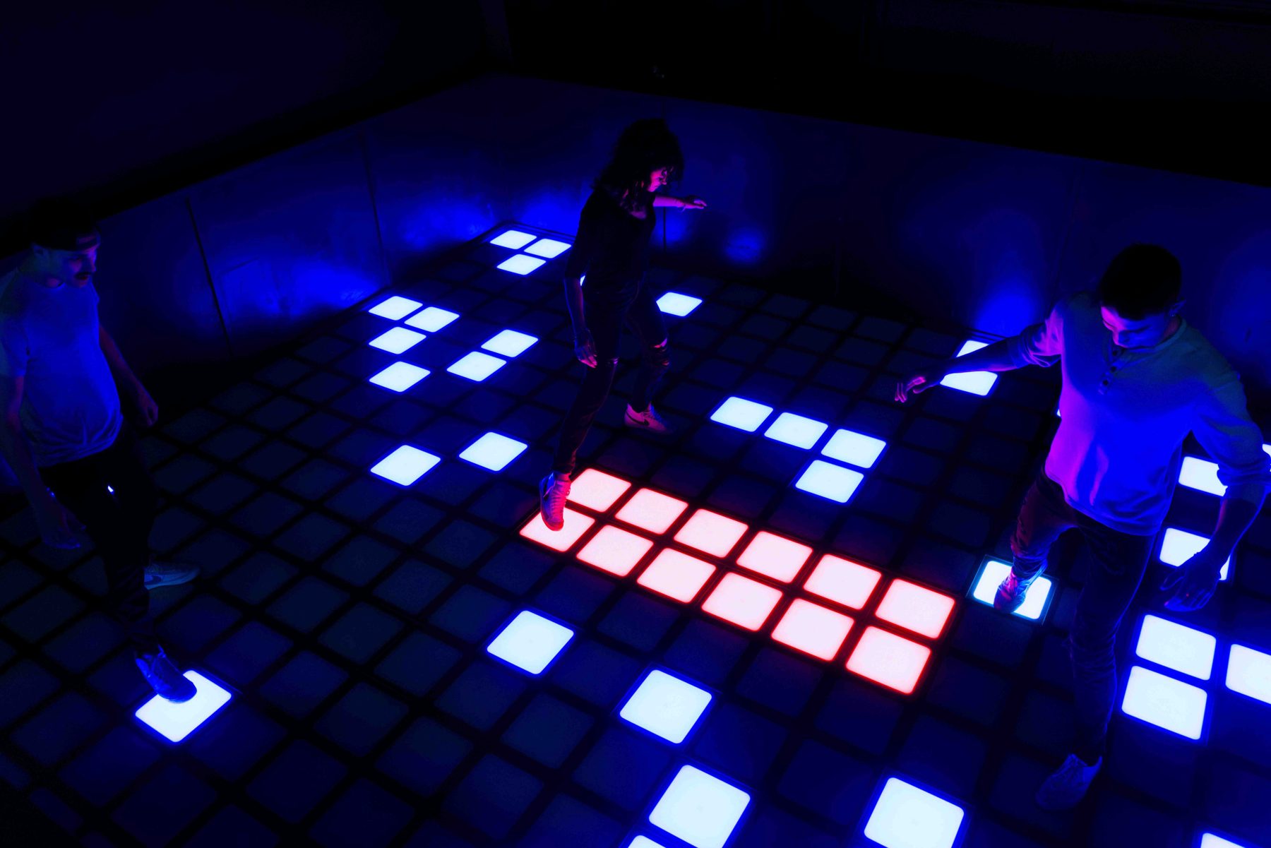 Players on the lit Pixel Floor game at Combat Ops